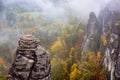 Picturesque autumn scenery with sandstone rocks and colorful trees covered by fog below.,Saxon Switzerland, Germany