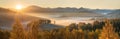 Picturesque autumn view, sunrise. Morning fog over a mountain valley, golden autumn. Panoramic