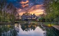 Picturesque big house situated on the banks of a tranquil lake, framed by lush greenery at sunset Royalty Free Stock Photo