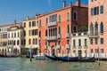 The picturesque embankment of the Grand Canal. Bright Venetian houses on the water, a pier with wooden gondolas. In the background Royalty Free Stock Photo