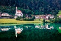 Picturesque evening view of Parrocchia di San Lucano Vescovo Catholic Church. Nice summer scene of Santa Caterina lake and Auronzo