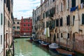 Picturesque facades of old buildings with hanging clothes and boats parked on canal in Venice, Italy, under blue sky with clouds o Royalty Free Stock Photo