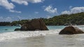 Picturesque granite rocks rise above the turquoise ocean in the surf.