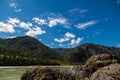 A picturesque landscape from the rocky bank of the Katun mountain river of turquoise color in Altai against a background of blue Royalty Free Stock Photo