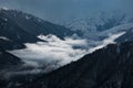 Picturesque landscape with snow-capped mountaintops and a few wispy clouds in the valley below