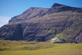 Traditional church surrounded by high mountains in village Saksun on Island Streymoy of the Faroe islands.