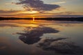 Picturesque morning sunrise with the rising sun and the reflection of colorful sky and clouds on the surface of a a lake Royalty Free Stock Photo