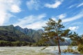 Picturesque mountain landscape on sunny summer day. River and rocky mountains against a blue sky. Pine tree stands in the water Royalty Free Stock Photo