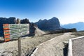 Picturesque mountain landscape with wooden trail marker in the foreground and a wide well-maintained hiking trail Royalty Free Stock Photo