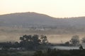 Mystical scenic hilltop landscape photograph with white and orange mist clouds under an orange sky Royalty Free Stock Photo