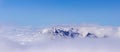 A picturesque, natural, minimalist landscape with a mountain peak above dense low clouds. The top of the mountain floats in thick Royalty Free Stock Photo
