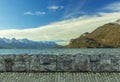 Picturesque nature wallpaper pattern concept of stone paved road and wall foreground frame scenic view on peaceful lake waters and Royalty Free Stock Photo