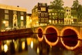 Picturesque Night View of Amterdam Cityscape with One The Canals Along With Illuminated Bridge and Traditional Dutch Houses At Royalty Free Stock Photo