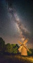 Picturesque nightscape of starry sky with Milky Way above an old wooden windmill Royalty Free Stock Photo