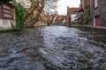 Picturesque old street of Bruges with traditional medieval houses, ivy, canal and bridges. Cityscape of Bruges streets shot from Royalty Free Stock Photo