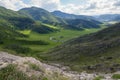 A picturesque place in the Altai Mountains with green trees and grass in the wild with a winding road at the foot under a blue sky Royalty Free Stock Photo