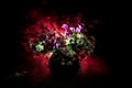 Picturesque purple spring flowers in glass vase standing in a row on a dark background with stars with light and fog. Flower conce