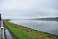 Picturesque river embankment in the fog cruise ships berth port, away lake autopedestrian bridge, thick clouds Royalty Free Stock Photo