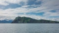 The picturesque rocky coast of Kamchatka against the background of blue sky and clouds. Royalty Free Stock Photo