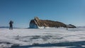 A picturesque rocky island with unusual outlines rises above a frozen lake.