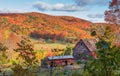 Picturesque rural barn atop a lush hillside, surrounded by vivid autumnal foliage.