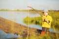 Picturesque scene of cute little boy fishing from wooden dock on magical lake at sunny summer day, vivid colors Royalty Free Stock Photo