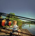 Picturesque scene of cute little boy fishing from wooden dock Royalty Free Stock Photo