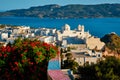 Picturesque scenic view of Greek town Plaka on Milos island over red geranium flowers Royalty Free Stock Photo