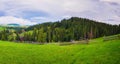 Picturesque spring Carpathians scene with wooden split rail fence across a green and lush pasture, and old cabins on the valley Royalty Free Stock Photo