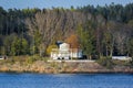 Picturesque spring coastal landscape of Stockholm archipelago with luxury waterfront villa named Elvira surrounded by bare trees