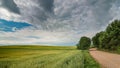 summer rural landscape. a dirt road along the agricultural field under a beautiful cloudy sky Royalty Free Stock Photo