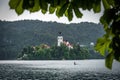 Bled lake with a Church of the Assumption of Mary view, and a girl on a paddleboard, in a frame of leaves in summer day time. Royalty Free Stock Photo