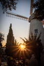 Picturesque sunset glows behind a vintage windmill atop a hill in a rural farm landscape in Jeru Royalty Free Stock Photo