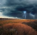 Picturesque thunderstorm over field near village. Dark cloudy sky with lightnings Royalty Free Stock Photo