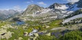 A picturesque valley in the Altai Mountains. Green alpine meadows, spring flowers, snow, lakes and creek. Panorama Royalty Free Stock Photo