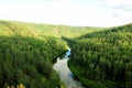 A picturesque view of the endless taiga from the top of the mountain and the calm river flowing below