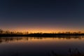 Picturesque view of Lake Claire surrounded by lush trees and foliage at sunset.