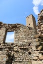 Picturesque view of old stone battle tower with the window of ruined house in abandoned village