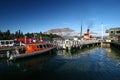 Picturesque view of orange water taxi and historic steamboat moored to piers in small town
