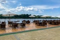 Picturesque view of outdoor cafe with rattan chairs and tables on shore of river Royalty Free Stock Photo