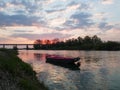 Picturesque view of the Sava River in Bosanski Brod with a boat moored in front and the silhouette of a forest and a bridge in the