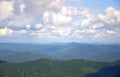 A picturesque view of the tops of mountain ranges overgrown with coniferous forest under a blue cloudy sky Royalty Free Stock Photo