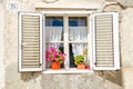 Picturesque window , shutters, colorful flowers against a white limestone wall Royalty Free Stock Photo