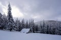 Picturesque winter landscape with huts, snowy mountains and forest.