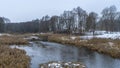 Picturesque winter or late autumn nature landscape with river, trees, dried yellow grass at cloudy frosty day. Royalty Free Stock Photo