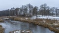 Picturesque winter or late autumn nature landscape with river, trees, dried yellow grass at cloudy frosty day. Royalty Free Stock Photo