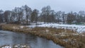 Picturesque winter or late autumn nature landscape with river, trees, dried yellow grass at cloudy frosty day. Royalty Free Stock Photo