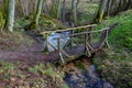 A picturesque wooden bridge across a stream in the middle of a deciduous forest. Crossing a small river Royalty Free Stock Photo