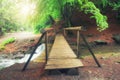 A picturesque wooden bridge across a stream in the middle of a deciduous green summer forest. Crossing a small river. Spring Royalty Free Stock Photo