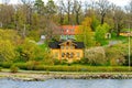 Picturesque yellow-framed wooden building in Swiss style named Eolslund villa with the sculpture of a black lion in the garden.